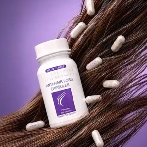 Bottle labeled 'Anti-Hair Loss Capsules' resting on brown hair with several white capsules scattered around, purple background (informational).