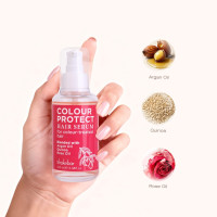 Hand holding a pink Colour Protect Hair Serum bottle with ingredient icons for Argan Oil, Quinoa and Rose Oil shown to the right.