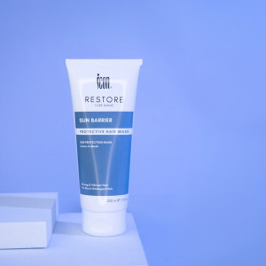 Tube of Icon Restore Sun Barrier Protective Hair Mask standing on a white surface against a blue background, label clearly visible.